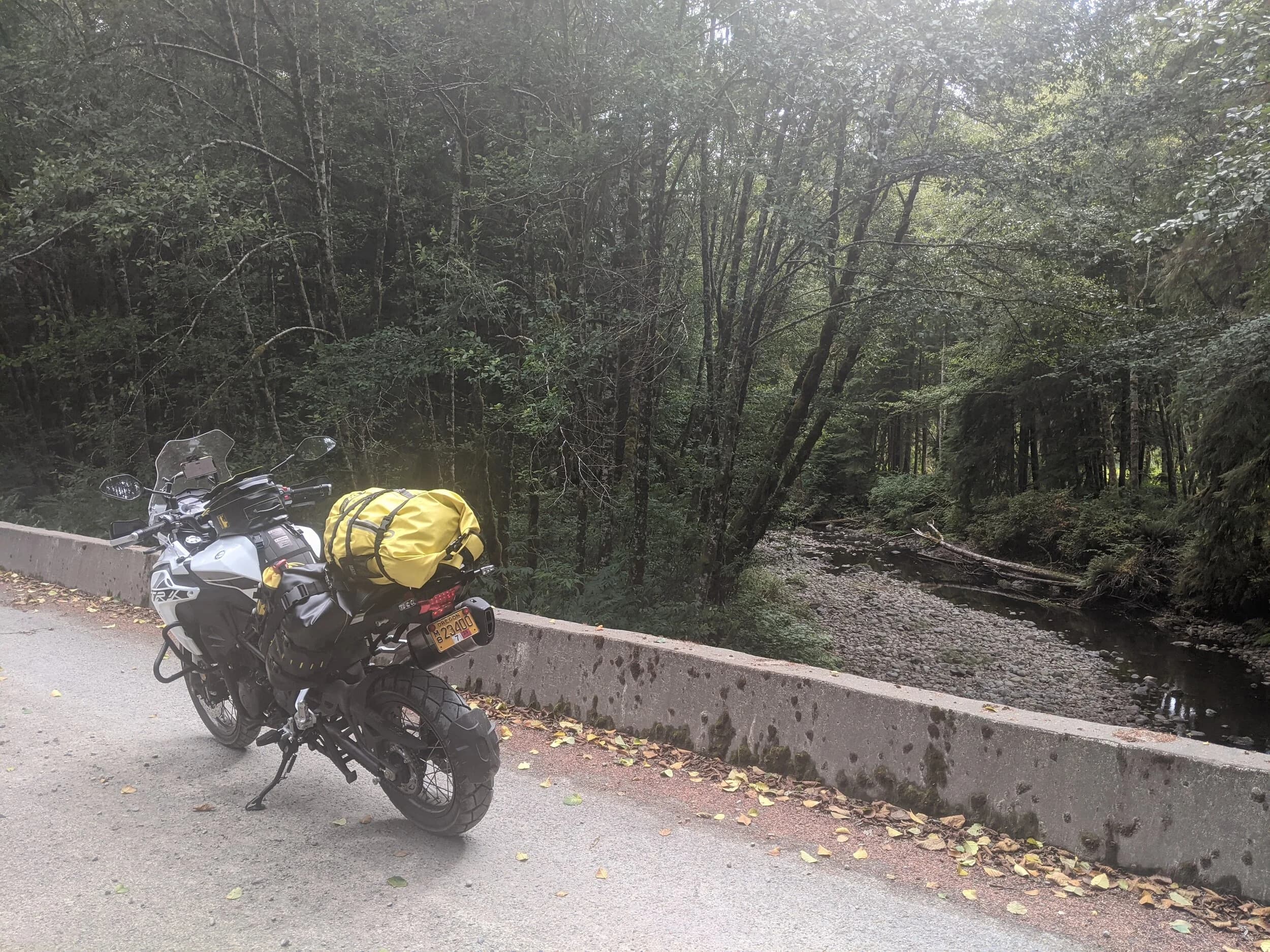 South Beach to Hoh Rainforest
This is the second installment of my trip log of my first overnight trip with the new Benelli TRK502X, doing 7 nights / 8 days from Portland, up the Olympic Peninsula, over to Bellingham and then finally to Orcas Island.
Day 3Planned Destination: Forks or La Push
Actual Destination: Hoh Rainforest Campground
Planned / Actual Accommodation: Camping
Planned / Actual Miles: 100 / 111
Planned Route: Follow the Oly Ride Guide Day Three route published by ADV Pulse, and camp somewhere near Forks or La PushRoute NotesAfter breaking camp I headed south to Queets to get gas and then back up US 101 to the store at Kalaloch to buy a sandwich for lunch for the day and pick up a few beers for the evening. I’d actually had trouble finding a place that was open and that sold beer the night before, so I was going into this day better prepared.
Today’s route was planned to be basically all of the Day 3 section of the ADV Pulse’s Olympic Peninsula route. No specific place planned to camp. I’d just find something when I was done for the day. The day started out well, and I got my first introduction to gravel roads and gravel two track on the TRK. After my experience on the WABDR on the Quota (which I haven’t written about, but I crashed hard; the Quota is in the garage patiently waiting to be rehabbed now), I was taking things slow and easy. The TRK isn’t that much lighter than the Quota, even though it’s half a liter smaller engine-wise, and I’m not sure yet if I can pick it up, so I didn’t want to get too excited and get myself into trouble again. Plus, I’m running the 80/10 Metzler Tourance tires that came on the bike; slow and easy.
I did build some confidence, but I never pushed hard. I thought about this a lot as I was riding actually. I mean, I could have pushed a lot harder. Why wasn’t I? The answer is simple. For me, adventure motorcycling (well, life in general) is about making moments. It’s about stringing together as many great memories as I can while I still can. I’ll remember the great views I “discover” along the way. I’ll remember the interesting people I meet. I’ll remember the trip. But I won’t remember if I pushed hard on any given day or not. I just don’t care about that anymore. Plus, when riding alone, you’re alone if you get into trouble. Better to go easy and get there in one piece.I did run into one issue along the way; the C-2000 road was closed. It appeared that my planned route was closed for the season, which hadn’t been noted in the ride guide. So, I backtracked to the Hoh Mainline Road and rejoined the planned route where Mainline meets Maple Creek Rd. I discovered later, upon closer inspection, that I’d actually missed a turn off of C-2000 (onto a road that isn’t labeled on the map) just before the road closure. Not sure how I rode past that turnoff twice without seeing it. So be it. I have an excuse to go back and do that again. It was all still great riding. Camp NotesIt’s been a while since I camped on the ground on a thin air pad, and it wasn’t really agreeing with me anymore; I hand’t slept well the last two nights. By the time I got to the Hoh Visitor Center I was tired and ready to be done. The Hoh Campground is reservation only, and there were no sites available when I was planning the trip. But, there was a sign at the visitor center beckoning visitors to inquire at the campground desk if there were any camp sites available, so that’s what I did.
I lucked out; there were several sites available. I got a great site with a somewhat secluded tent space (though I worried about tent flooding as it was several feet lower than the surrounding land; fortunately there was no rain). I met a young couple who were actually sleeping in their car. Ouch. They didn’t really know how to camp. She was from Texas but had recently moved to Eugene, Oregon, and he was from England somewhere. She said she was an artist and she’d never done anything like this before. In the morning, she came over and asked if I had a way to heat water so they could have coffee. I obliged.
The guy next to me also came over in the morning and offered me coffee. Motorcycle travel really brings out the friendliness from people in RV trailers. Gear NotesI had noticed a store on the road up to the Hoh visitor center. I rode back to see if they had any food, as I was running low. I hadn’t really been thinking ahead and replenishing food before I needed it, and I was worried that I’d run out. The store had several freeze dried meals, so I picked up something for dinner and some scrambled eggs for breakfast, leaving the food I already had for the next day.
I didn’t have a ton of room for food as I was storing all food (and smelly items) in a small Bare Boxer bear canister from Gossamer Gear. Since I wasn’t running with hard case luggage, I felt I needed a way to keep the rodents (and bears) at bay. The Bare Boxer has room for two days of dinners and breakfasts (freeze dried) plus coffee, some extra oat meal, energy bars, my toothbrush & paste, the dish soap, DEET, and my Whisperlite stove. It worked out quite well the entire trip, actually. Anything that might attract rodents or bears went in the canister, and the canister fit nicely at the bottom of my left-side Wolfman 20L rolie.
As noted above, sleeping on the ground on a thin air pad doesn’t do it for me anymore. My back killed me on the third night, and I did not sleep well at all. I have identified the solution, however. The Helinox Lite Cot. It packs smaller than my air pad and is now on my Christmas wish list. The only downside would be cold weather camping; will need a thin foam pad to provide insulation for temps below freezing, likely.